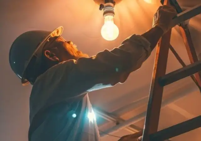 Electrician on a ladder fitting a ceiling light