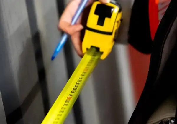 Measuring tape held against a wall before electrical work